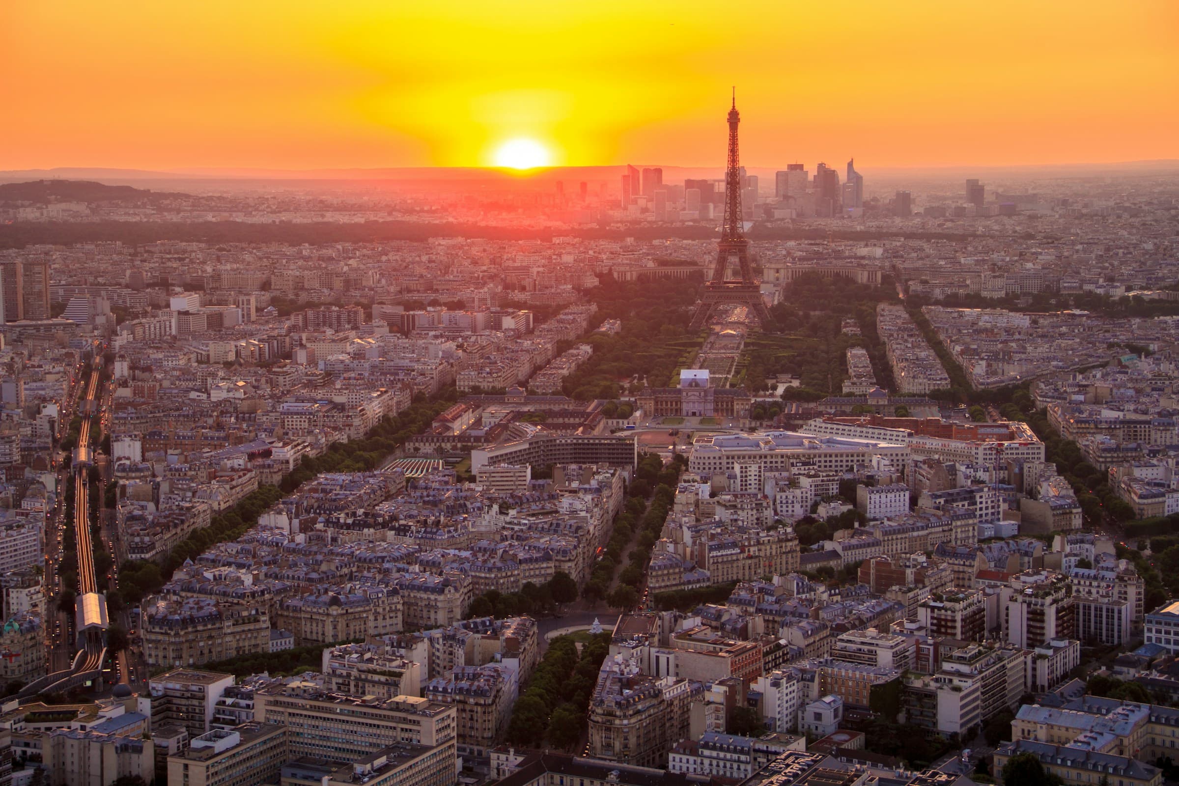 Aerial view of Paris at sunset from the Montparnasse Tower, with the Eiffel Tower above the avenues and rooftops